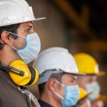 uomini con casco e mascherina al lavoro